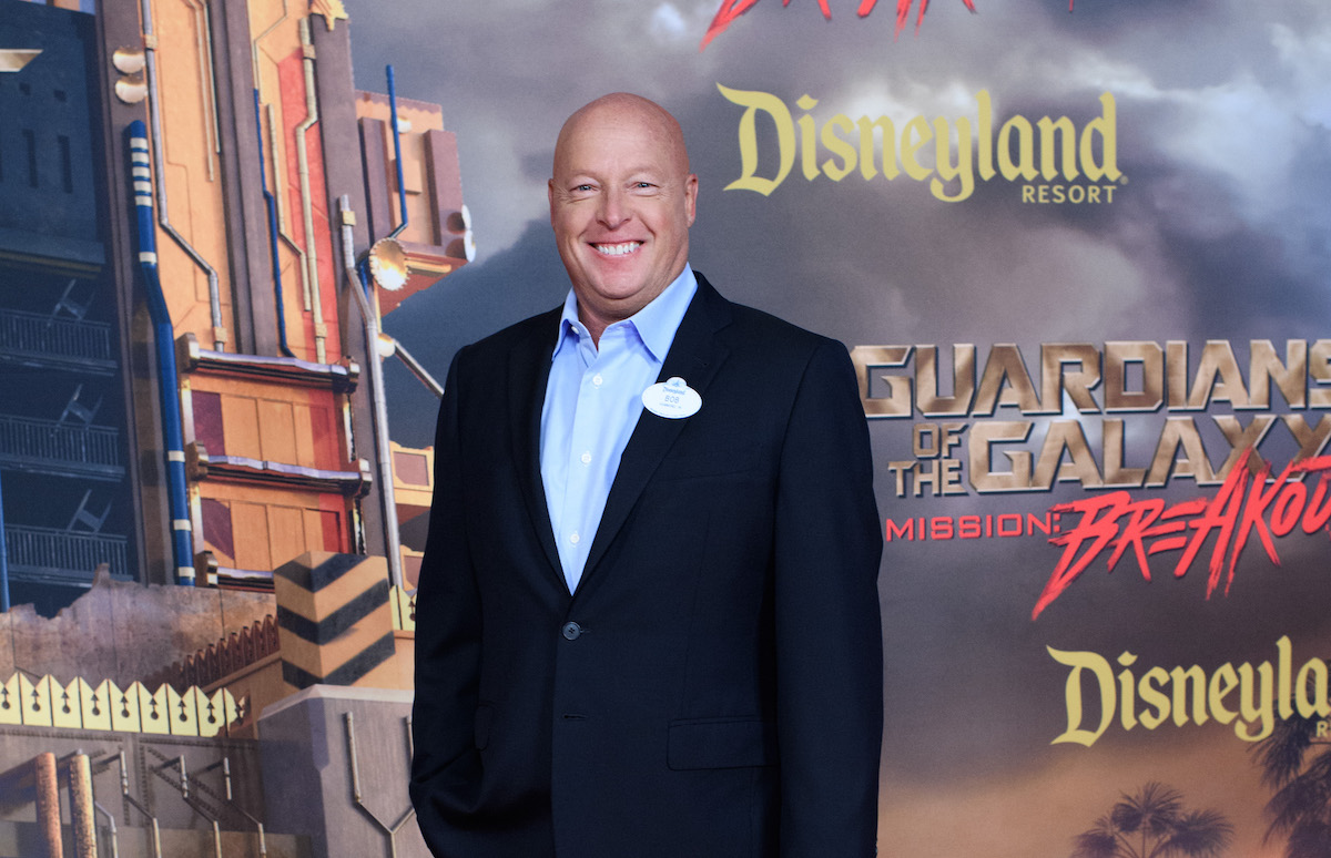 A white man (Bob Chapek) stands in front of a red carpet promo wall for Guardians of the Galaxy: Mission: Breakout ride.