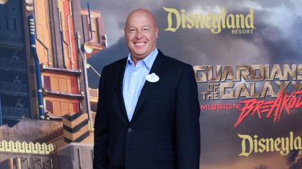 A white man (Bob Chapek) stands in front of a red carpet promo wall for Guardians of the Galaxy: Mission: Breakout ride.