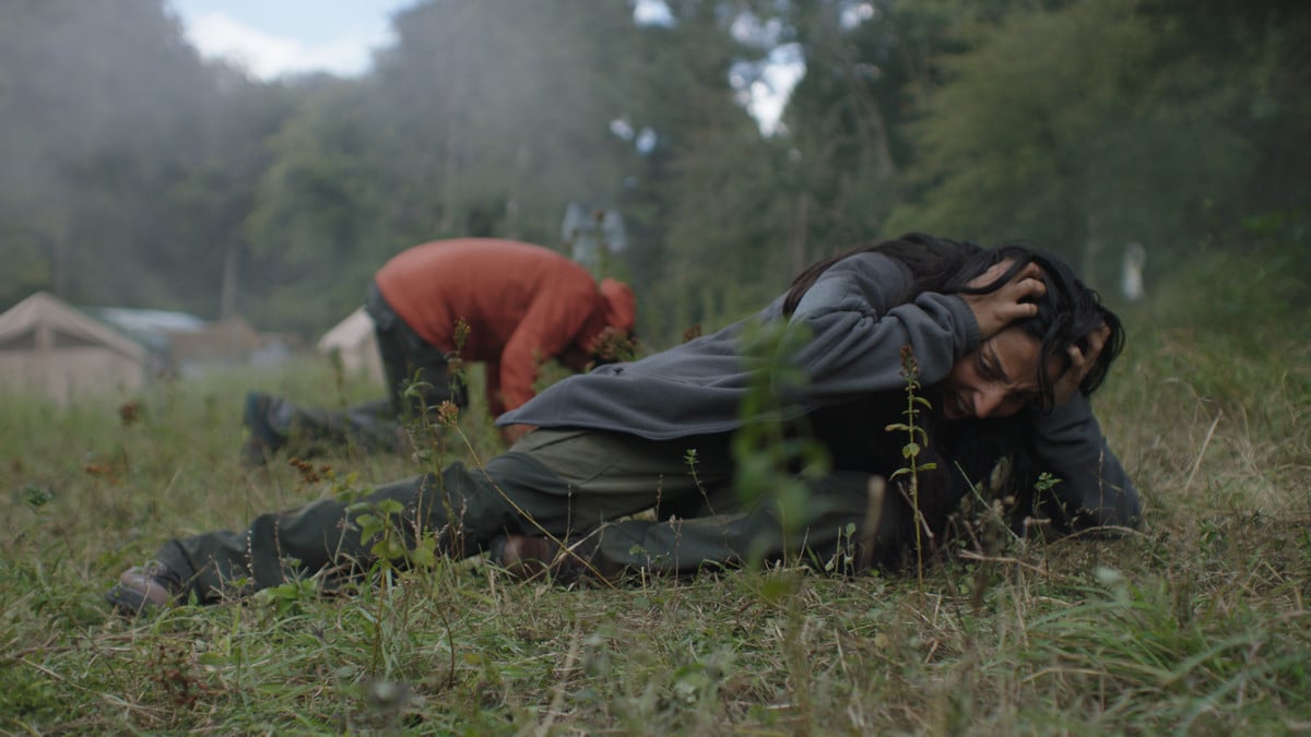 Alma and Martin lie on the grass, clutching their heads in agony in 'In the Earth'