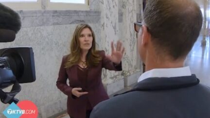 Janice McGeachin puts out her hand silencing a reporter during a hallway interview.