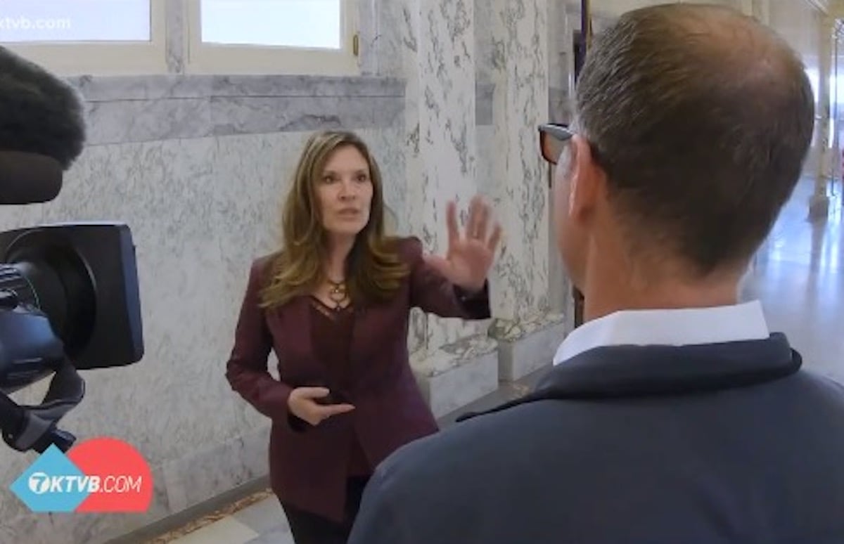 Janice McGeachin puts out her hand silencing a reporter during a hallway interview.