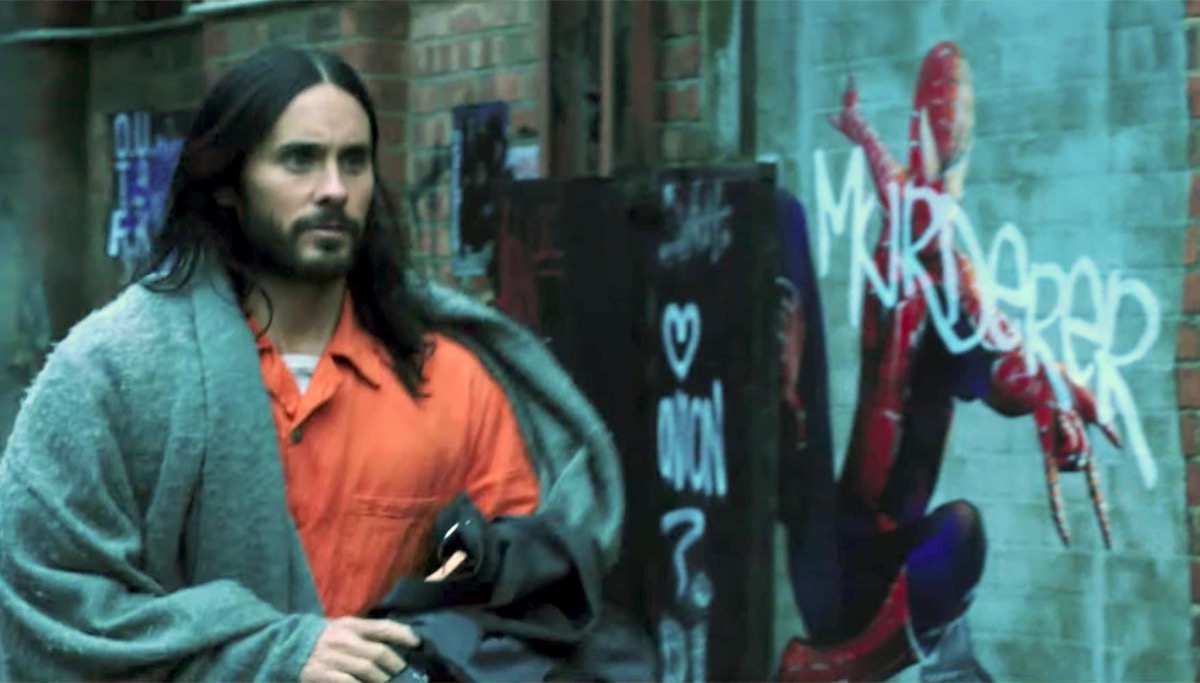 Jared Leto in Morbius, walking by a Spider-Man poster with "murderer" spray-painted across it.
