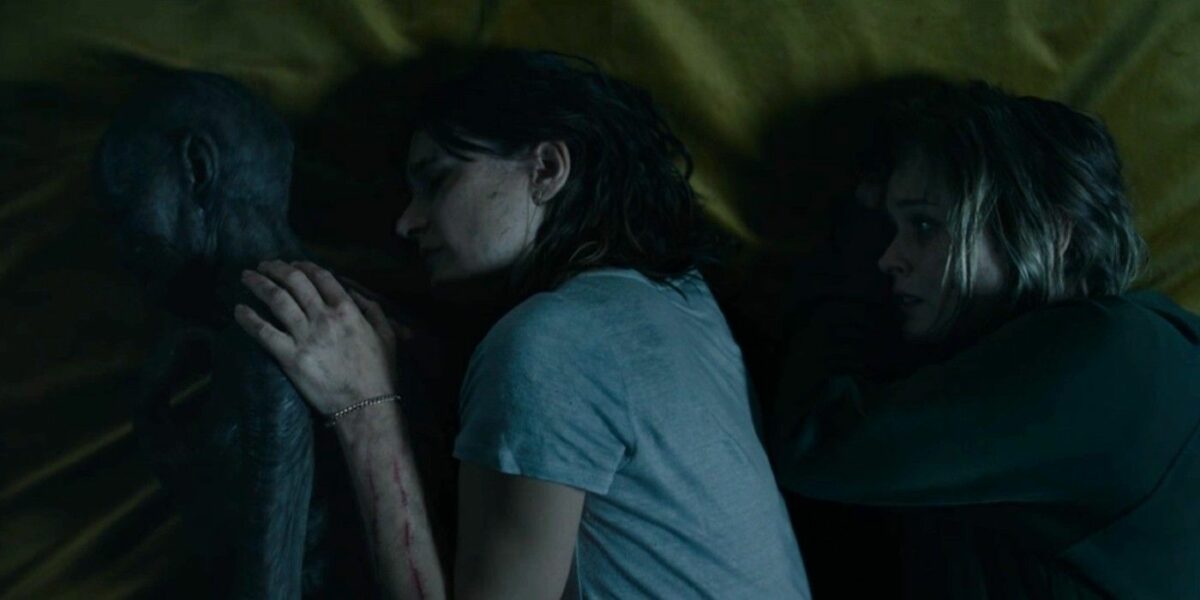 Mother, daughter, and grandmother spoon on a bed. Grandmother is completely covered in black mold.