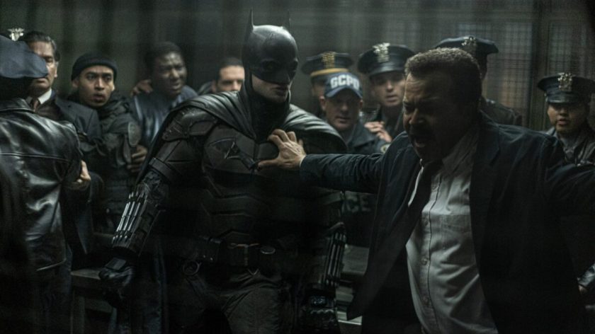 Jim Gordon holds back Batman and a crowd of Gotham police officers