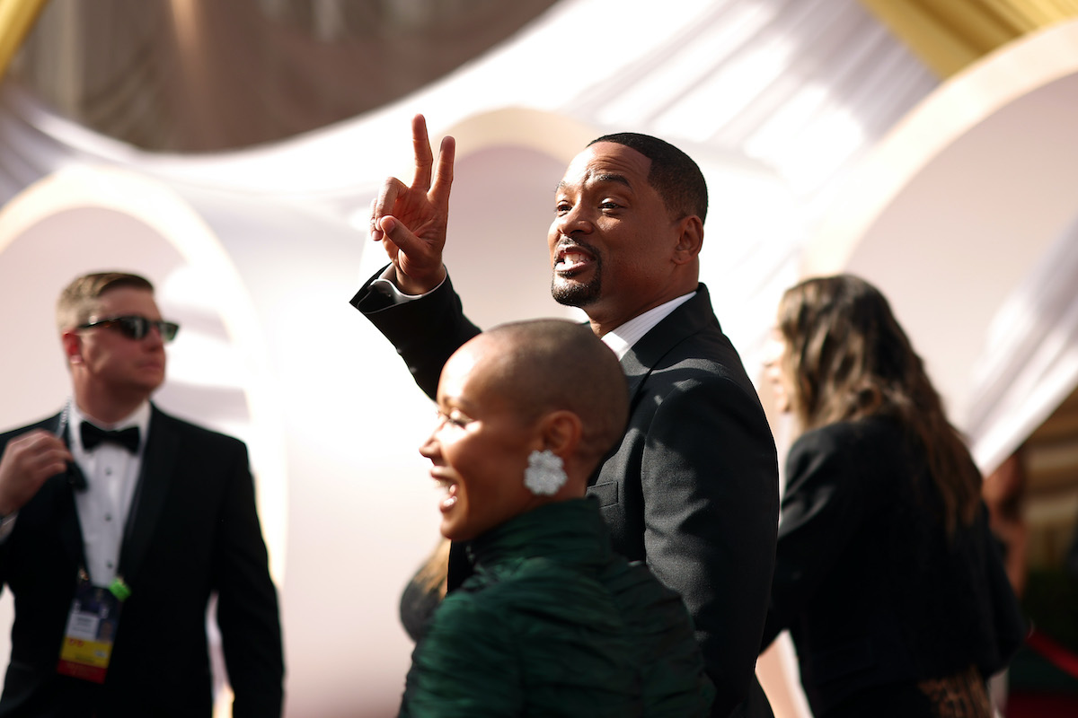 Will Smith flashes a peace sign as he and Jada Pinkett Smith walk the Oscars red carpet