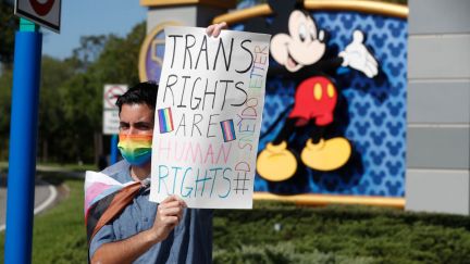 A protester outside Disney holds up a sign that says 'Trans Rights are Human Rights' in Florida