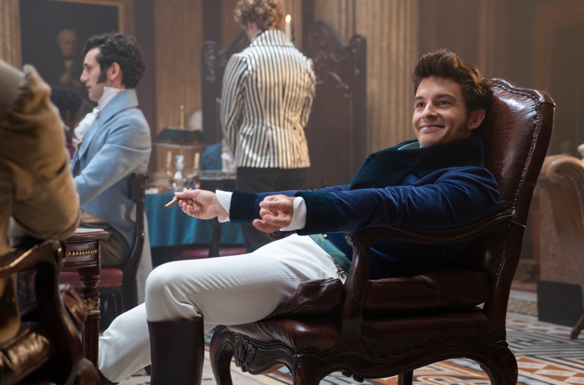 Anthony Bridgerton sits back in a chair, smiling.