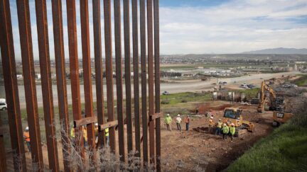 A section of border wall, made of tall beams, under construction