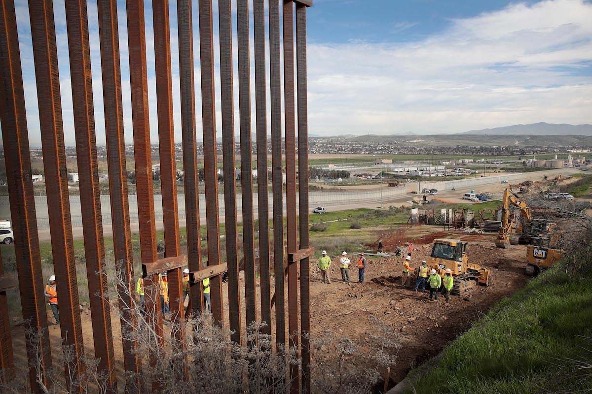 A section of border wall, made of tall beams, under construction