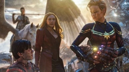 Captain Marvel taking the Infinity Gauntlet from Spider-Man as Scarlet Witch and Valkyrie look on in Marvel's Avengers: Endgame.