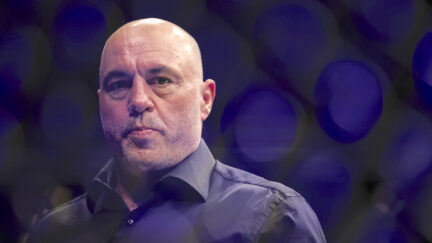 Joe Rogan looks serious against a dark background