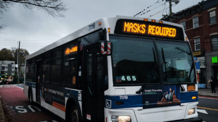 A bus displays a message noting masks are required to board