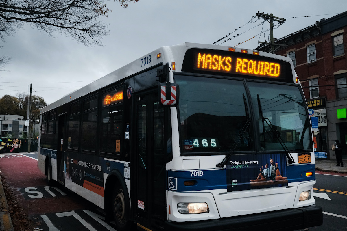 A bus displays a message noting masks are required to board