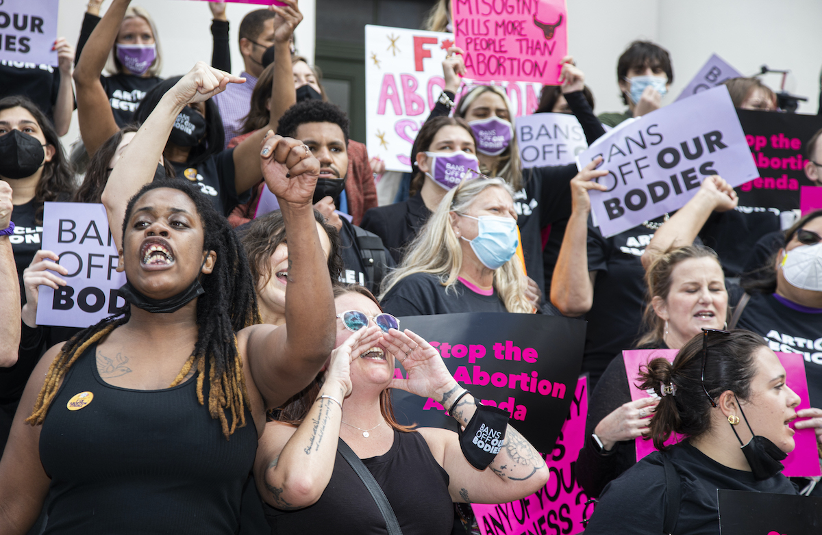 A group of protesters rally for abortion rights with raised fists and signs.