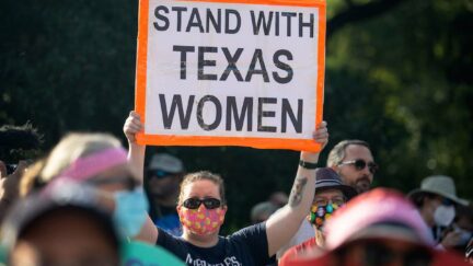 At a rally, a protestor holds a sign reading 