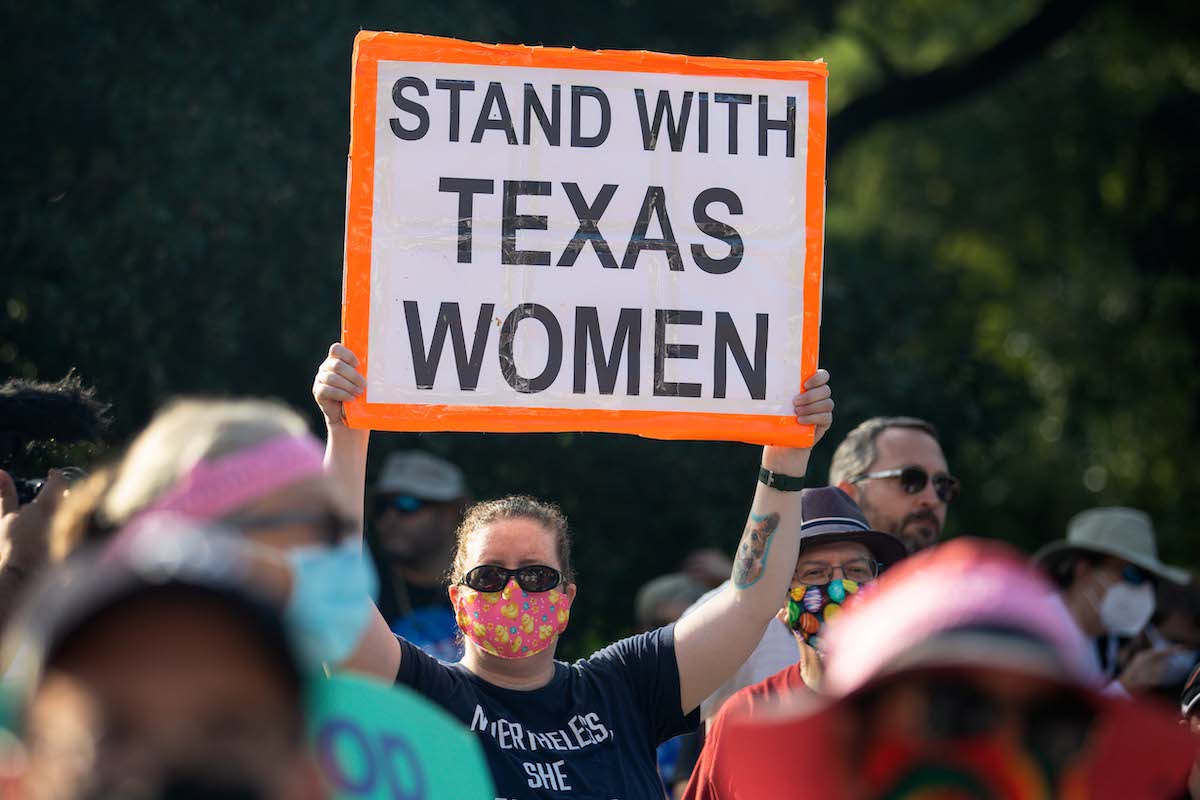 At a rally, a protestor holds a sign reading "stand with texas women)