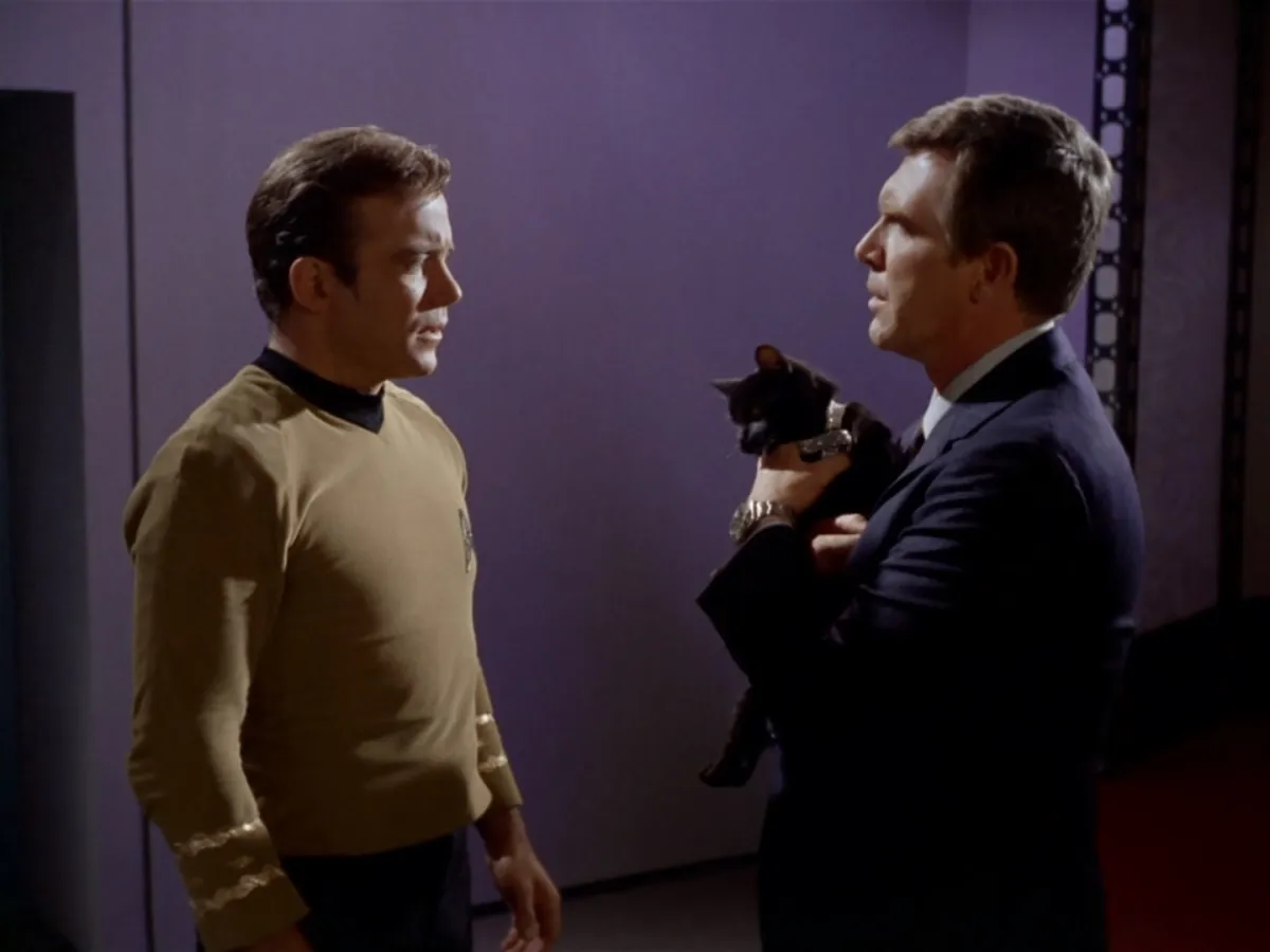 Kirk looks at Gary Seven who is holding his cat Isis