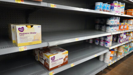 Store shelves are mostly empty, with just a few packages of baby formula on display.