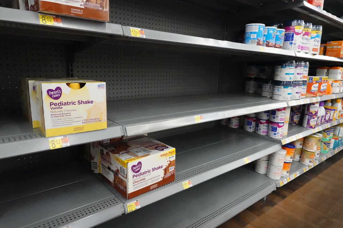 Store shelves are mostly empty, with just a few packages of baby formula on display.