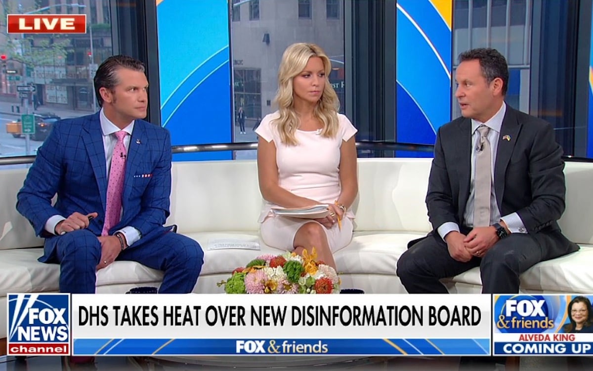 The three hosts of fox & friends sit and talk at each other in their studio.