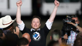 Elon Musk raises his fists in the air