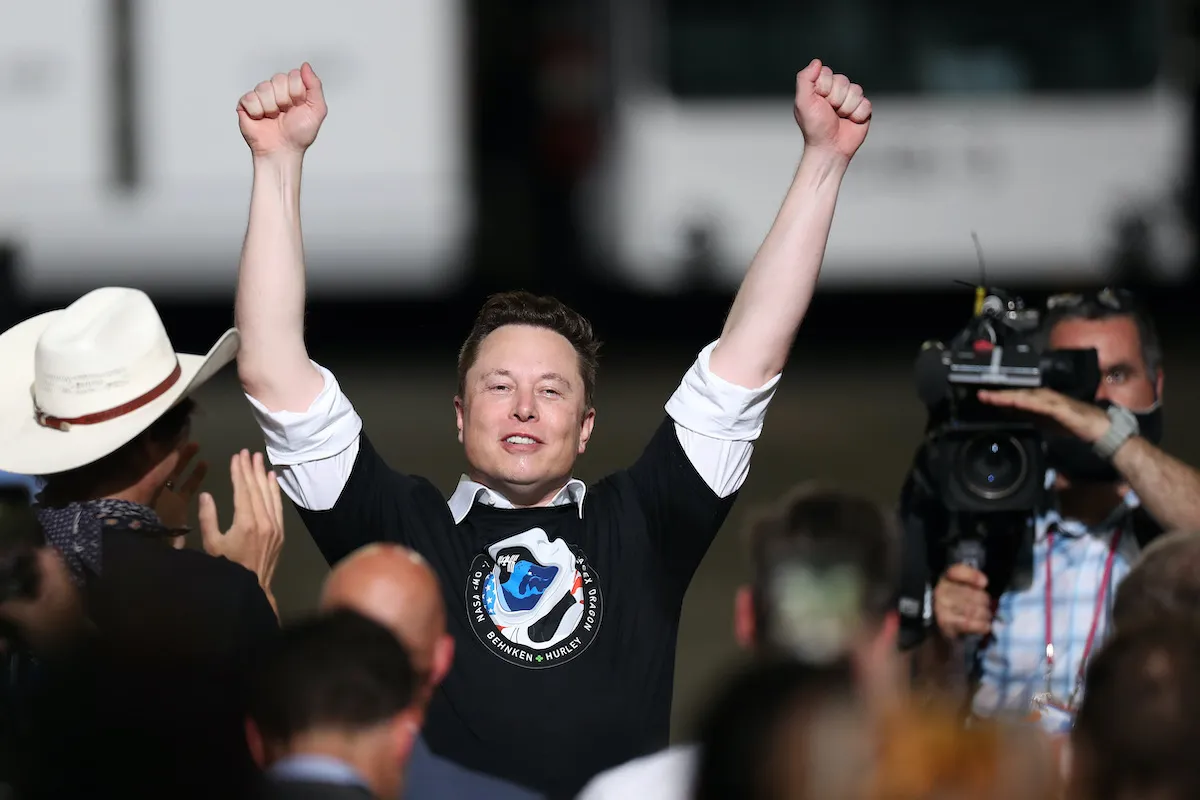Elon Musk raises his fists in the air