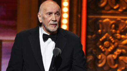 Frank Langella wears a tuxedo while standing at a podium on stage.
