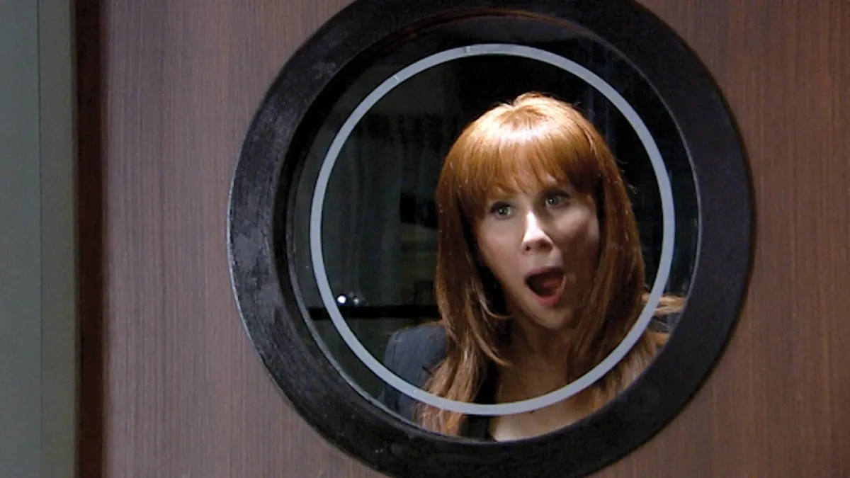 Donna looking excited in a round window in Doctor Who.