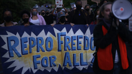 Abortion rights protesters march holding a banner reading 