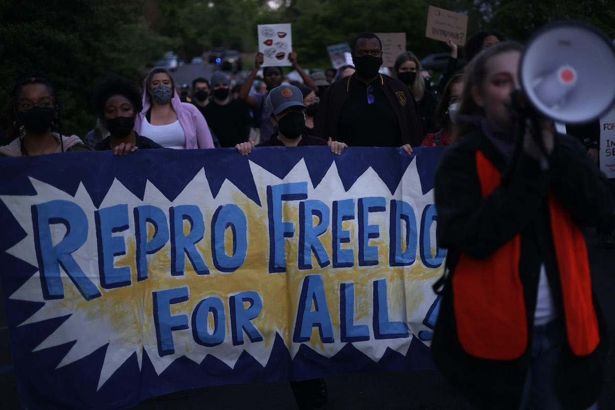 Abortion rights protesters march holding a banner reading "Repro freedom for all"