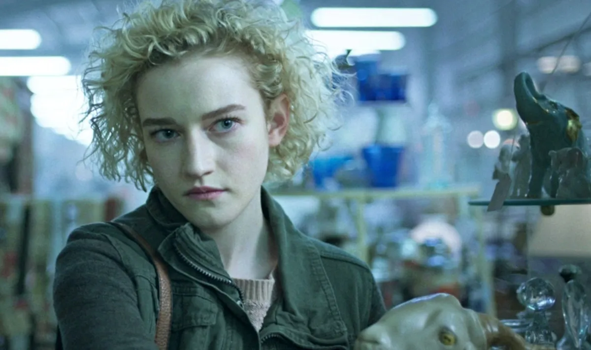 A blonde curly haired white woman stands in a store holding a ceramic goat head.