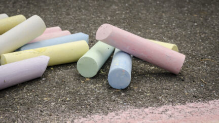 Colored chalk on asphalt lying.