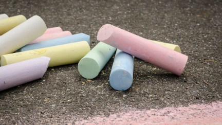 Colored chalk on asphalt lying.