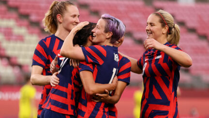 Members of the US Women's National Soccer team hug on the field