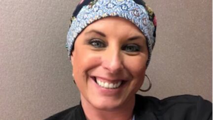 A woman in a headwrap smiles at the camera.