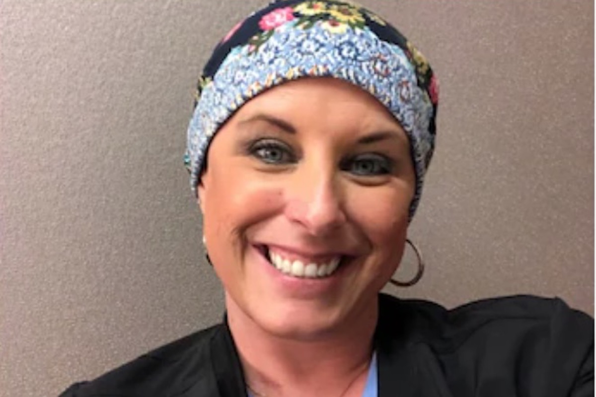 A woman in a headwrap smiles at the camera.