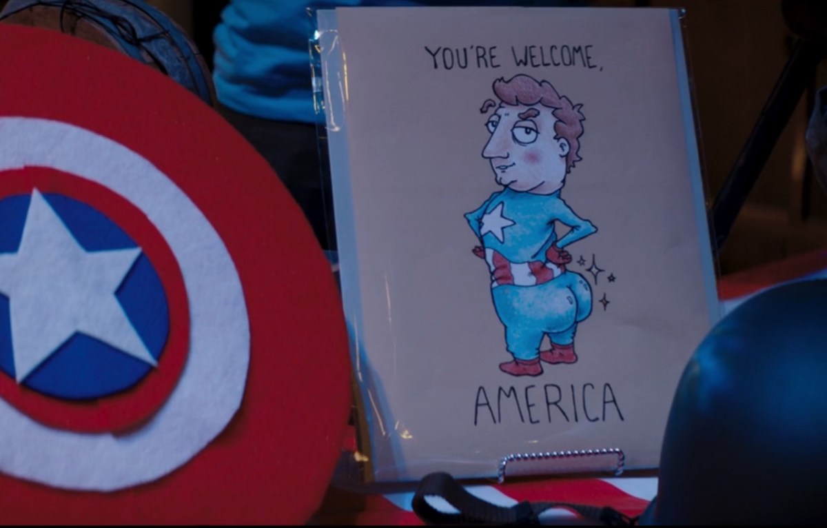A greeting card with a cartoon of Captain America sticking his butt out, with the words "You're welcome, America." Next to him is a felt shield.