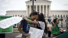Abortion rights protesters hug and cry outside of the Supreme Court.