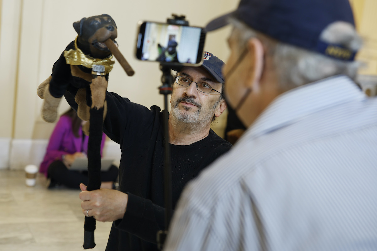 Actor and comedian Robert Smigel performs as Triumph the Insult Comic Dog in a hallway, being filmed by a cameraman