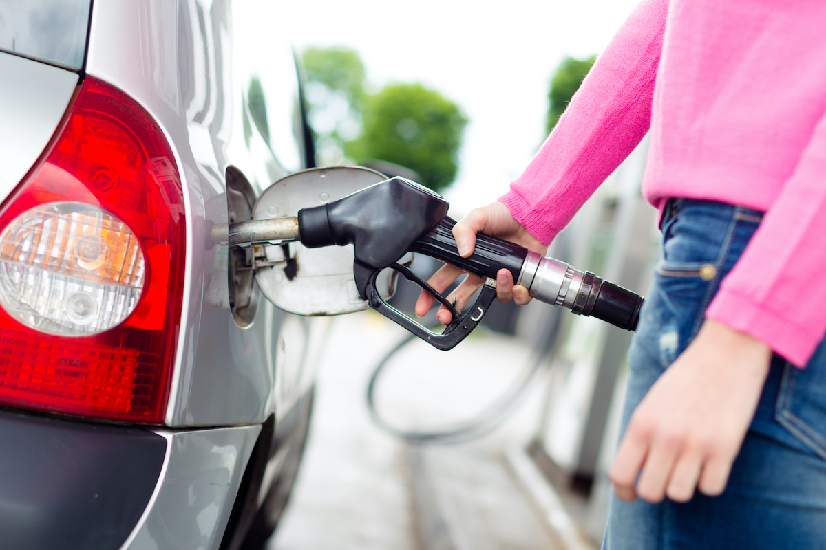 Closeup of woman pumping gasoline fuel in car at gas station