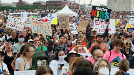 A large crowd of protesters march with gun safety signs