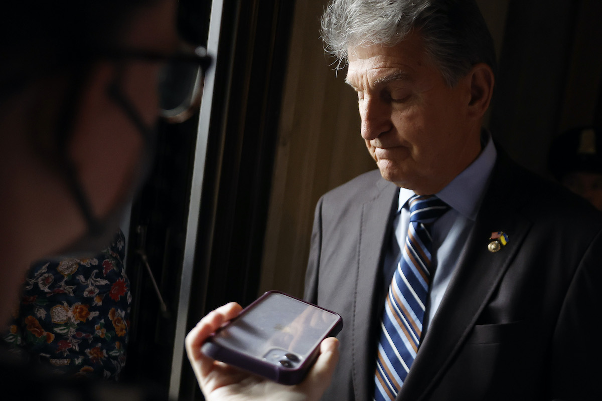 Joe Manchin looks disappointed while talking to reporters.