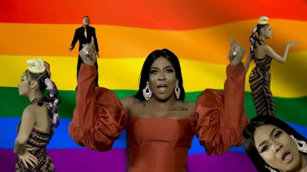 Angel Maxine singing her song Wo Fi in front of a large LGBTQ+ flag. Image: screencap.