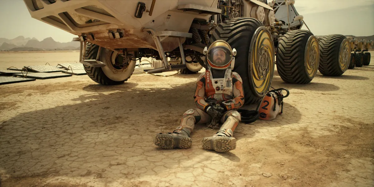 Matt Damon sitting against a martian rover in 'The Martian'