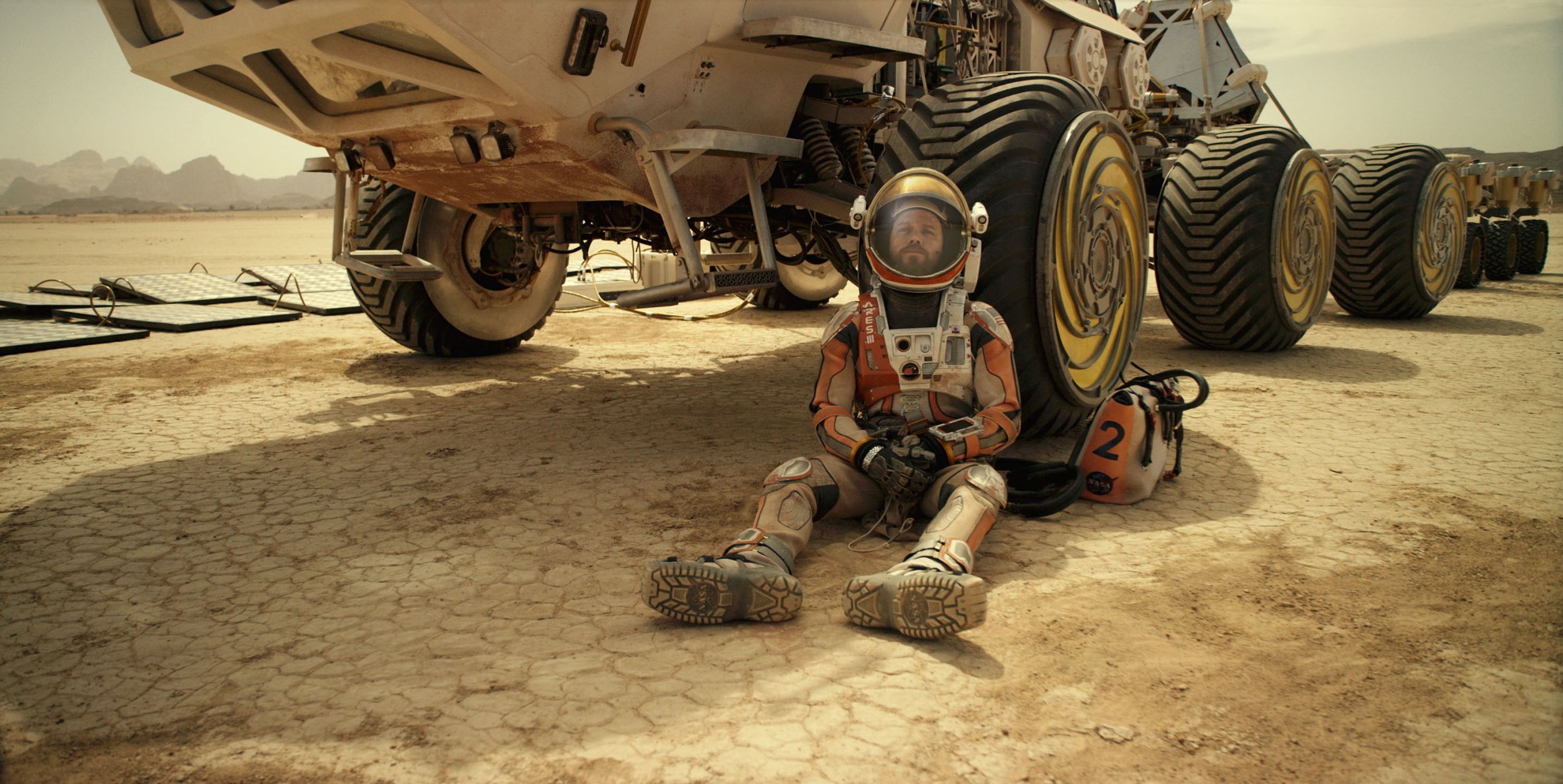 Matt Damon sitting against a martian rover in 'The Martian'