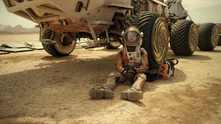 Matt Damon sitting against a martian rover in 'The Martian'