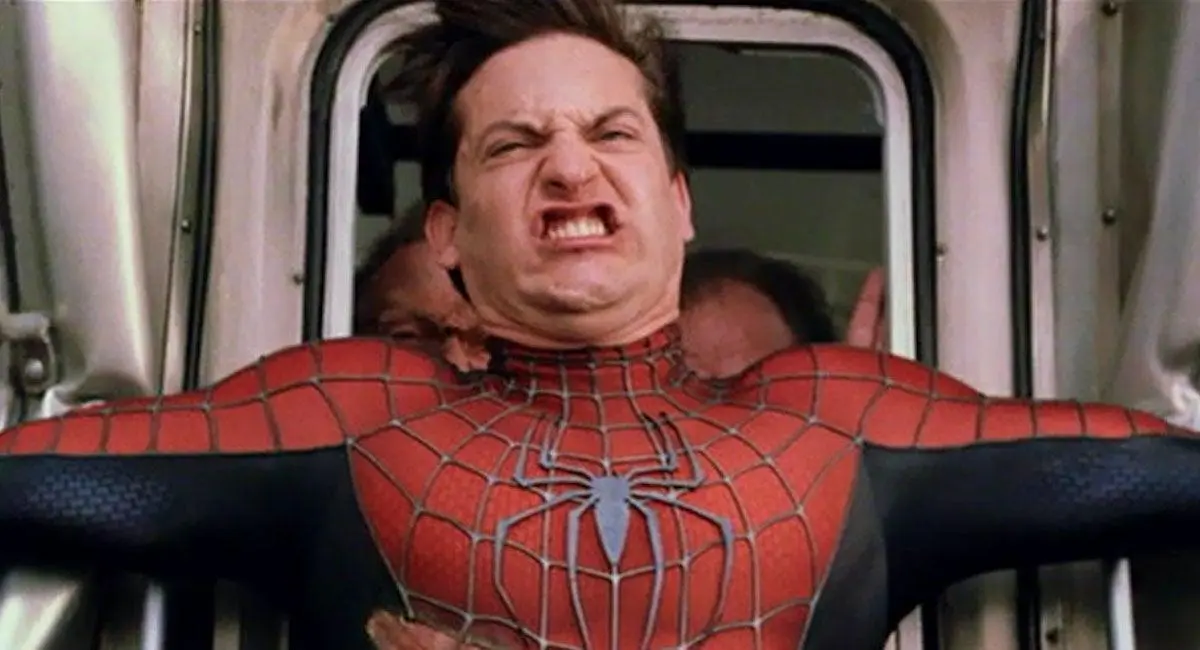 Tobey Maguire as Spider-Man grimacing as he tries to stop a train.