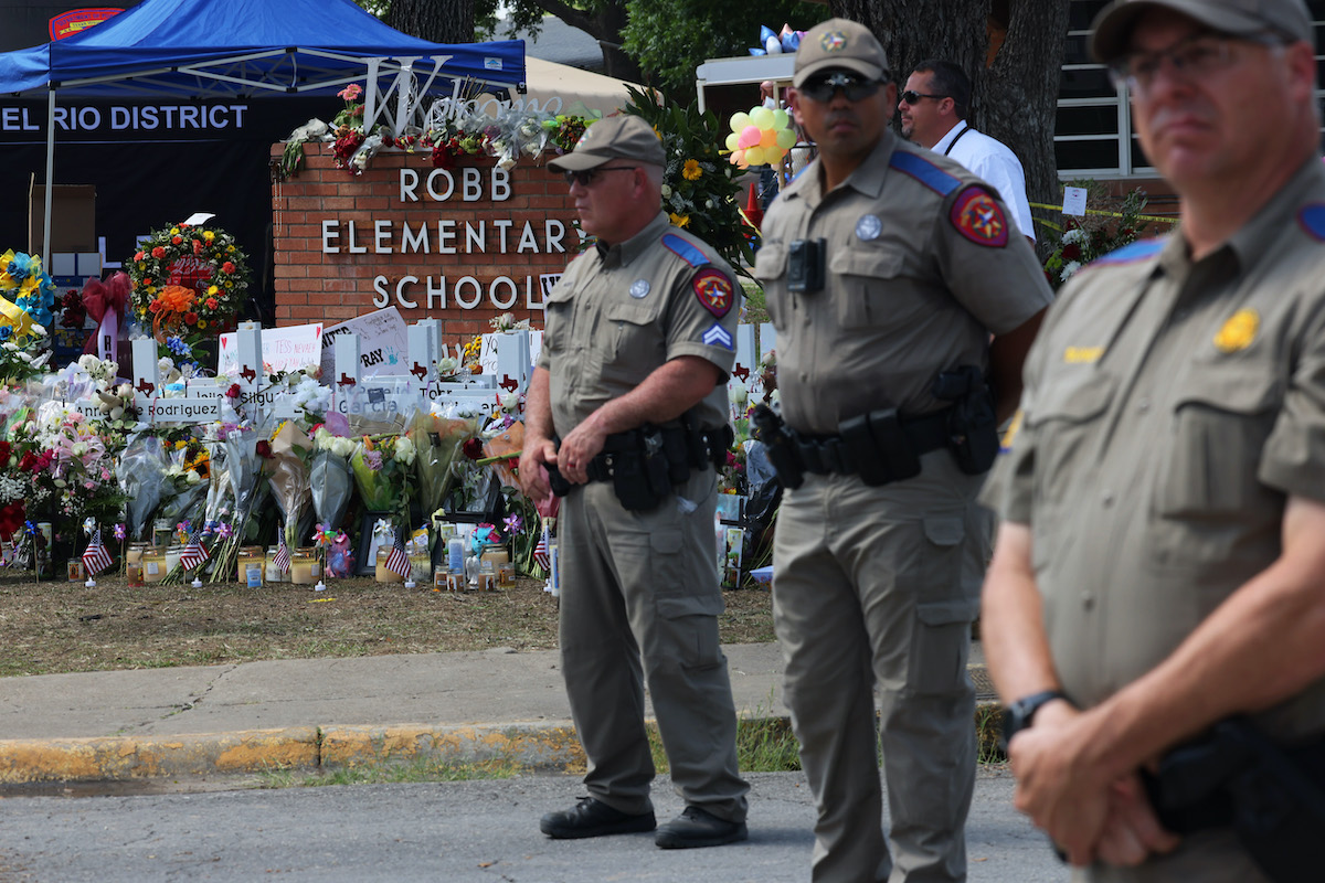 Texas Highway Patrol Troopers stand at attention in front of a memorial for the victims of the mass shooting at Robb Elementary School