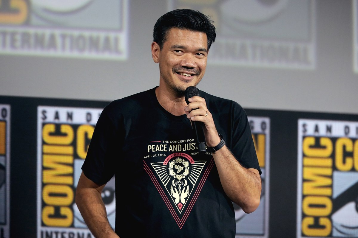 Destin Daniel Cretton standing on stage with a microphone at San Diego Comic-Con.