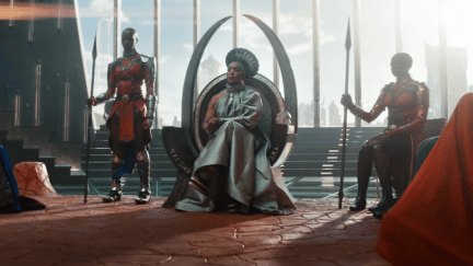 Queen Ramonda (Angela Bassett) sits in her throne, flanked by two Dora Milaje.
